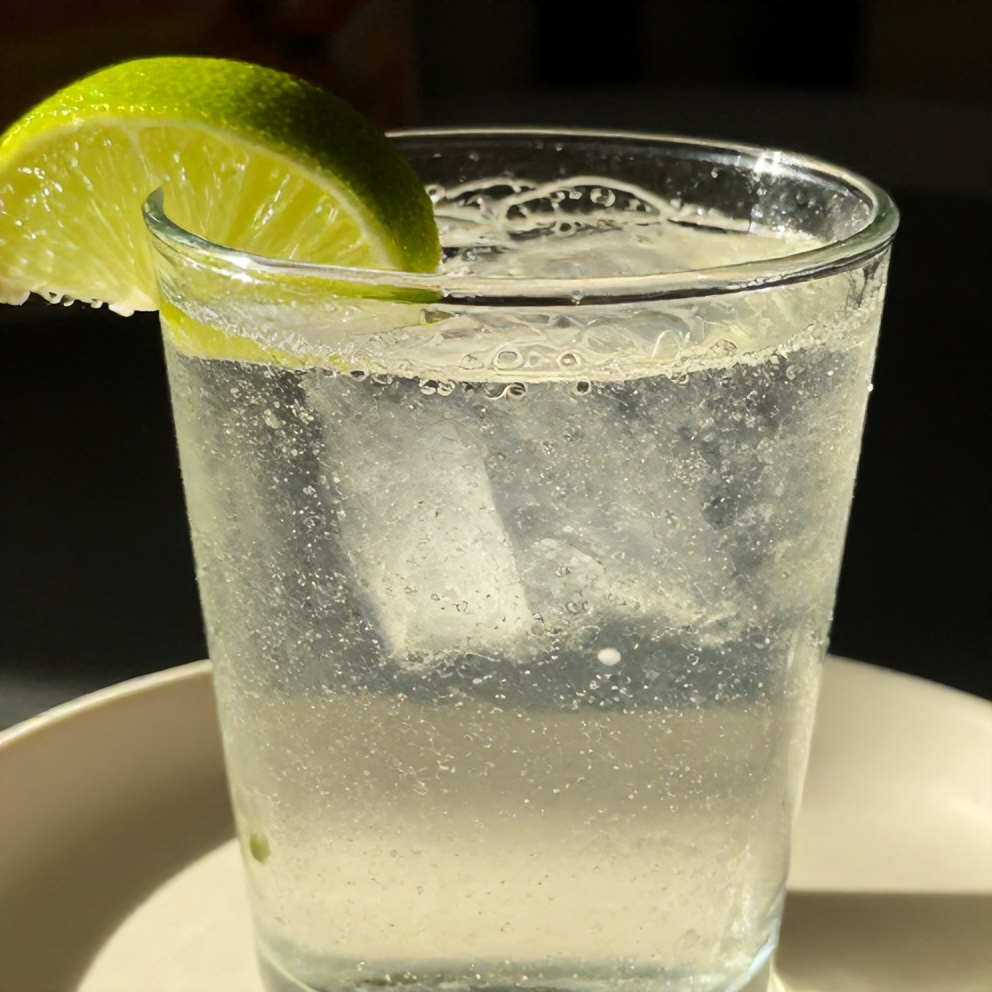 Glass of sparkling water with lime wedge garnish