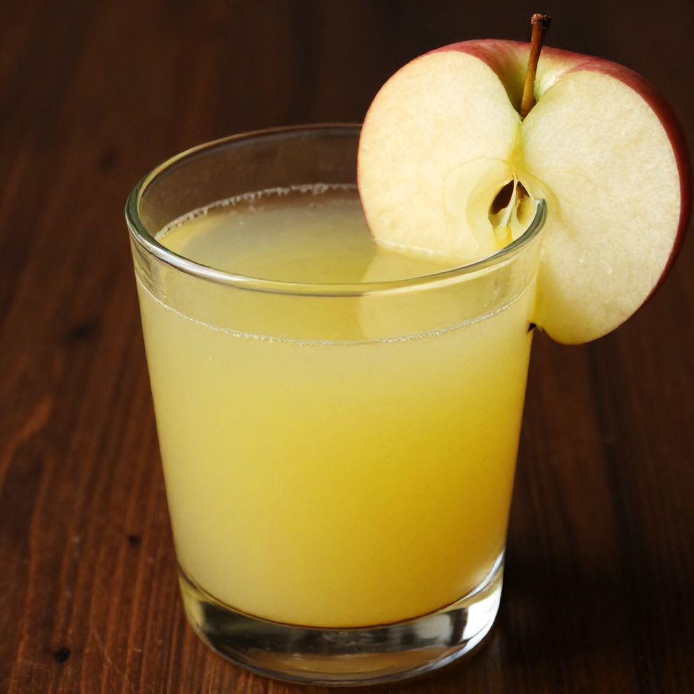 Glass of celery apple juice with a slice of apple on the rim