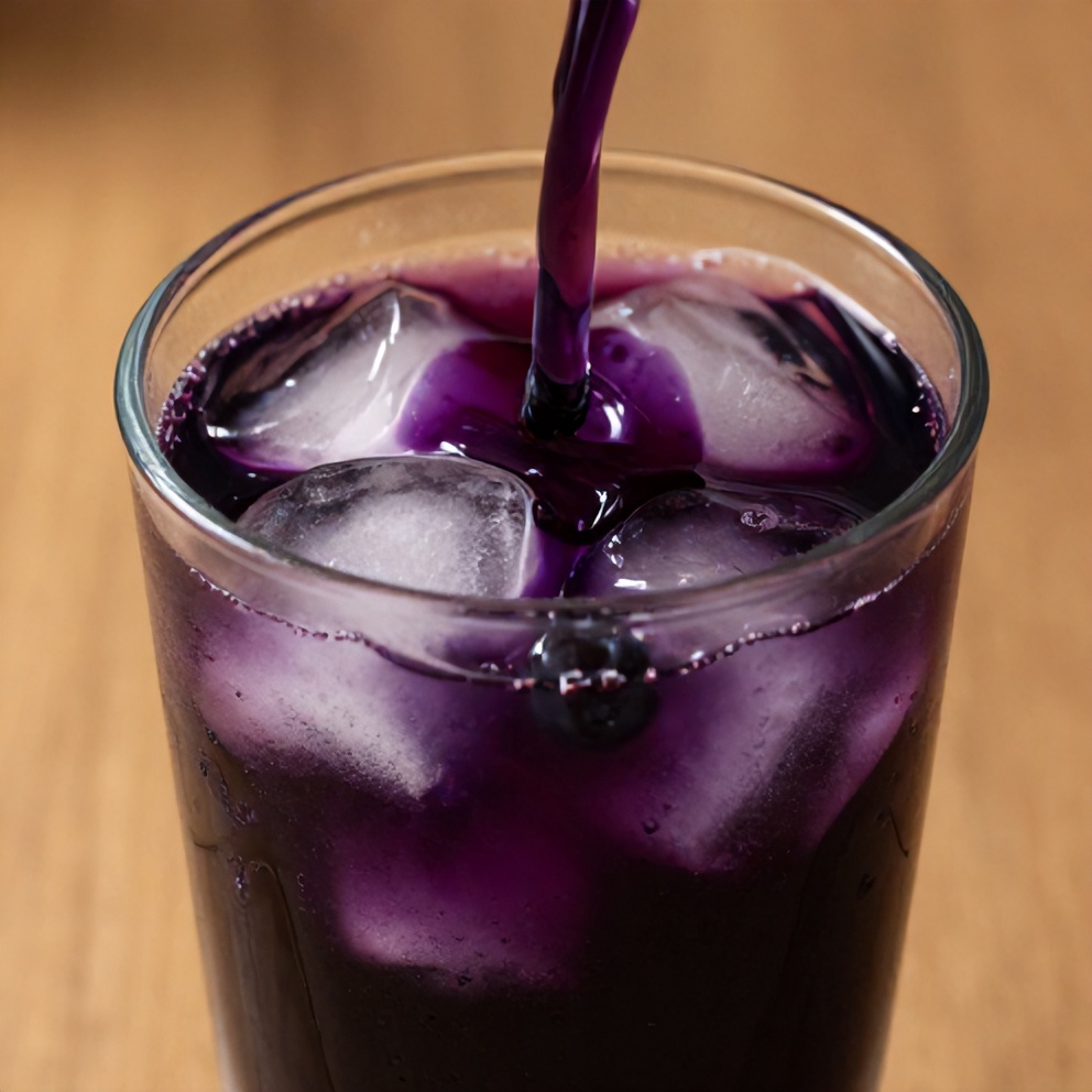 Blueberry syrup poured over ice in a glass