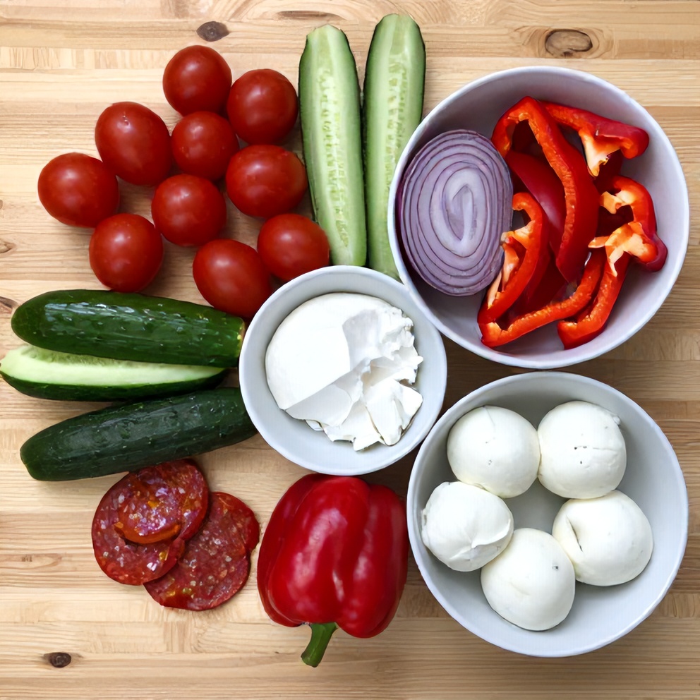 Raw ingredients for Classic Italian Pasta Salad laid out on a wooden surface