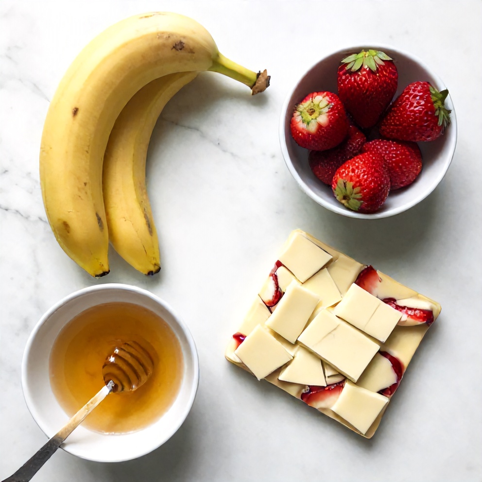 Raw ingredients for strawberry banana bark on a white marble surface
