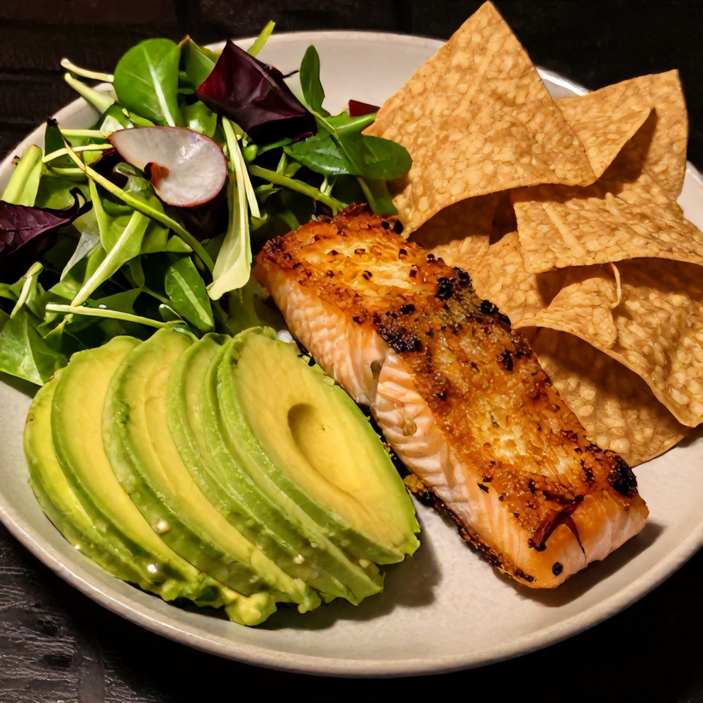 Crispy salmon bowl with avocado sauce, mixed greens, and tortilla chips