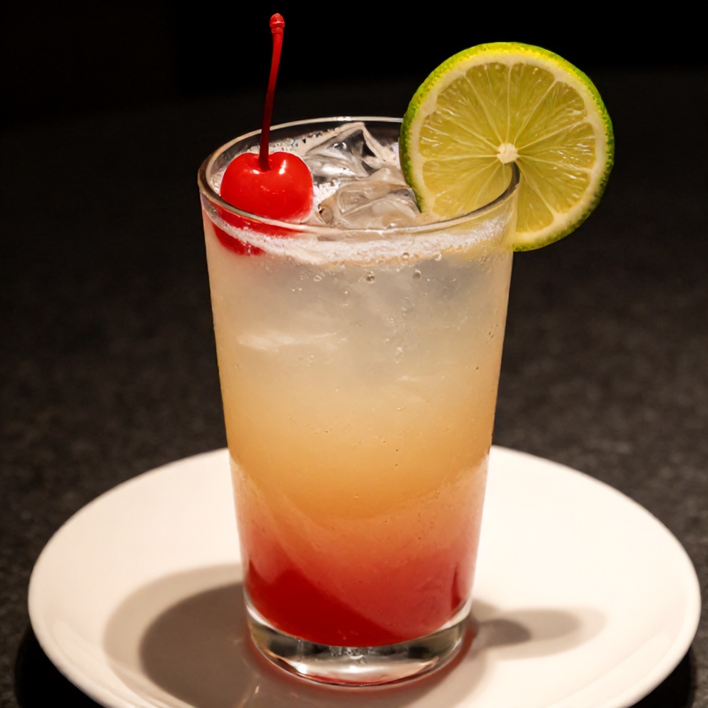 A glass of cherry limeade with a cherry and lime garnish